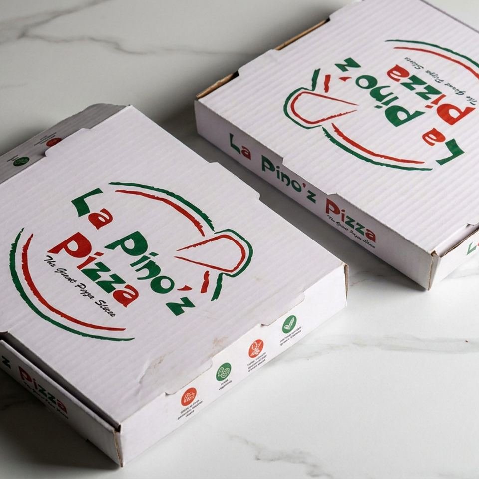 Two La Pino’z Pizza delivery boxes sit on a white marble surface, displaying the restaurant logo and colorful printed labels.